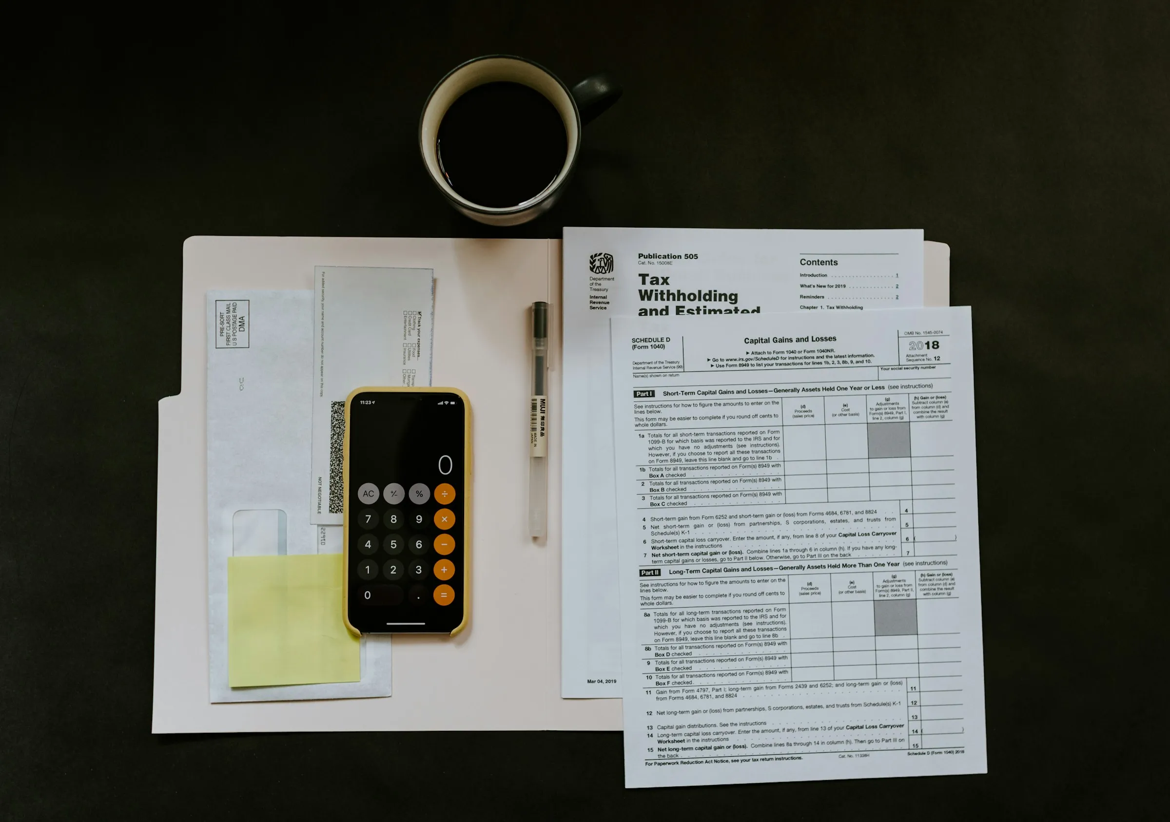 Formularios de impuestos, una carpeta, una calculadora y un café sobre una mesa oscura